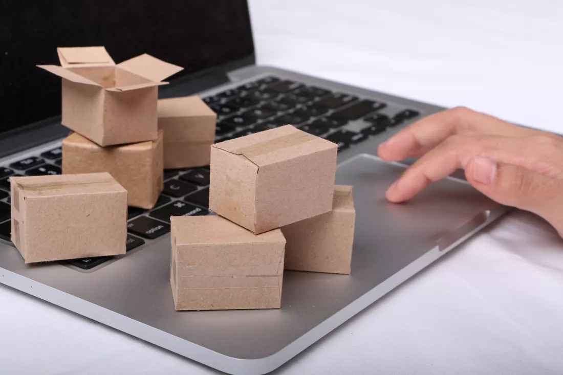 close-up-hand-using-laptop-with-cardboard-boxes-desk