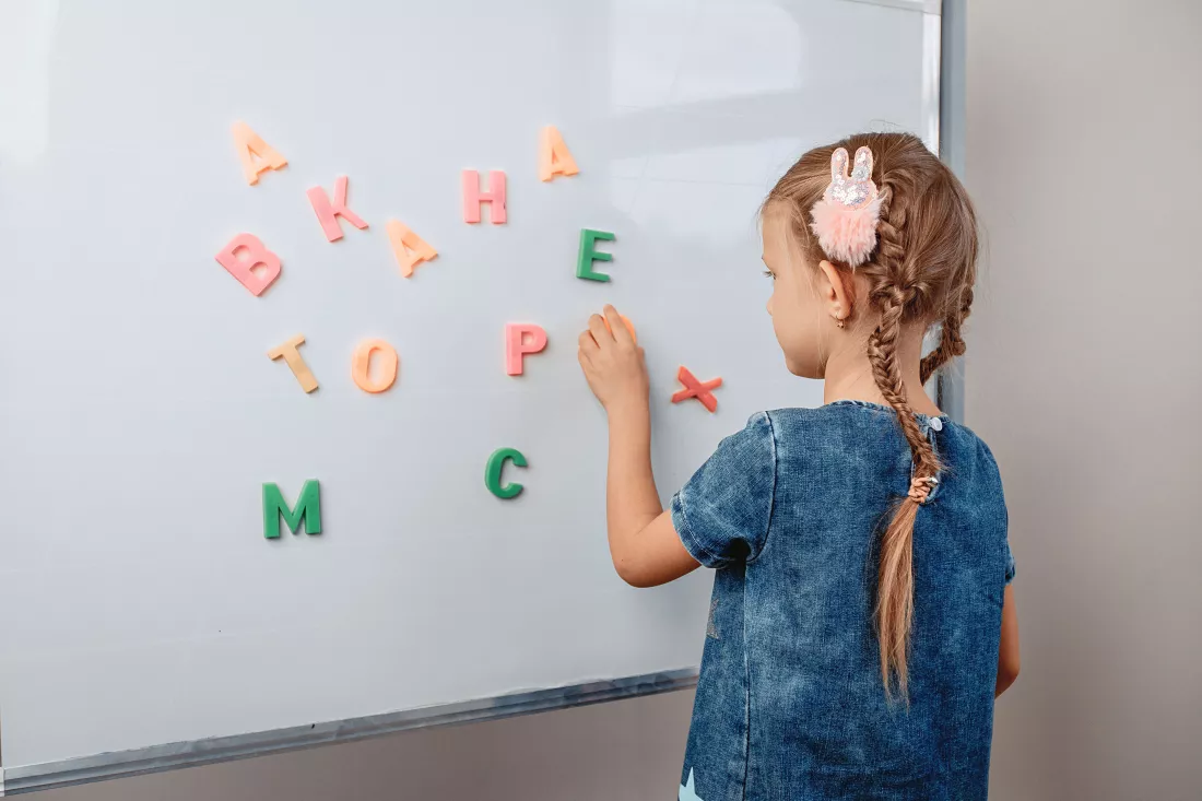 portrait-focused-intelligent-lovely-kid-standing-front-white-board-with-alphabet-letters-correct-order-focus-concept