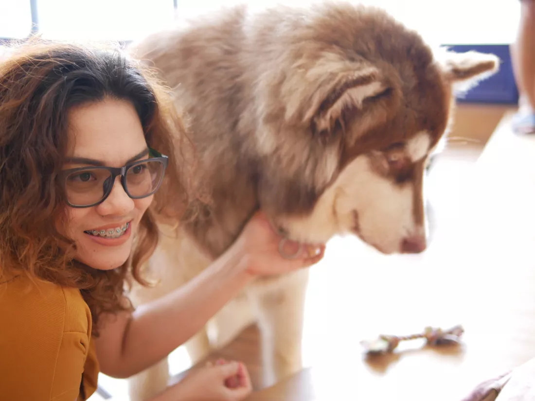 smiling-woman-stroking-dog-while-looking-away-home