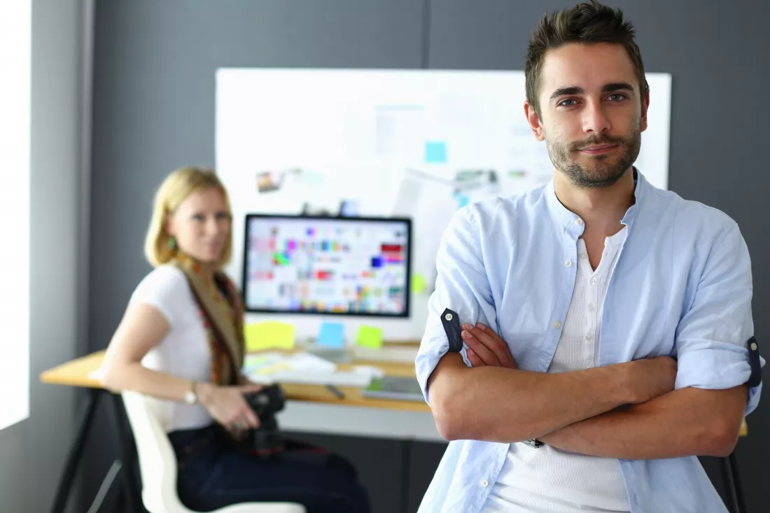 portrait-young-designer-front-laptop-computer-while-working-assistant-using-her-mobile-background